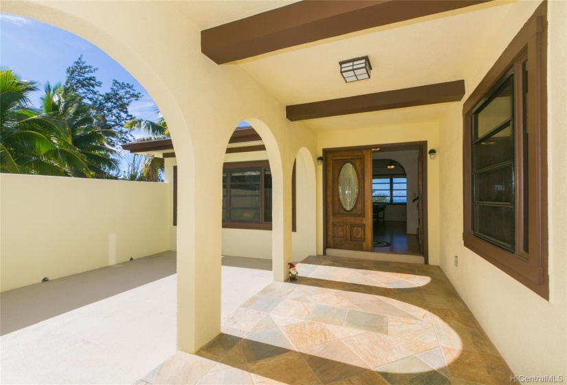 This majestic entry has an open private walled lanai and a covered entry of natural stone! The double door entry with stained glass beckons you into the interior!