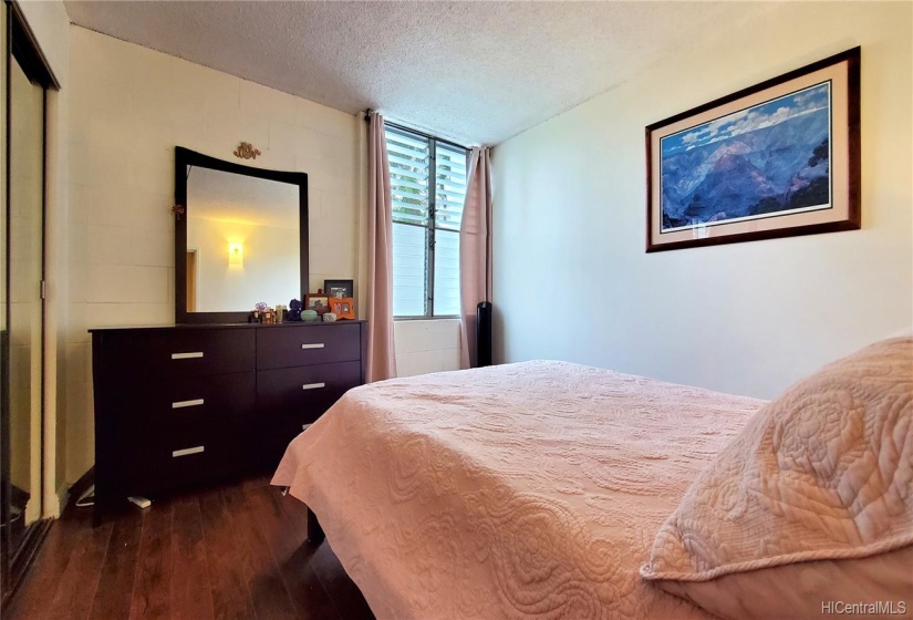 Main bedroom w/ mirrored closet doors and wood laminate floors