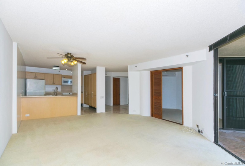 Looking from the far end of the living area, through dining area, into the kitchen. Lanai is on the far right, double door at center right is bedroom #2. At far back, the closed door is a large walk-in panty.