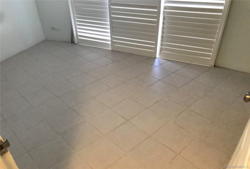 Bedroom with ceramic tile flooring and shutter