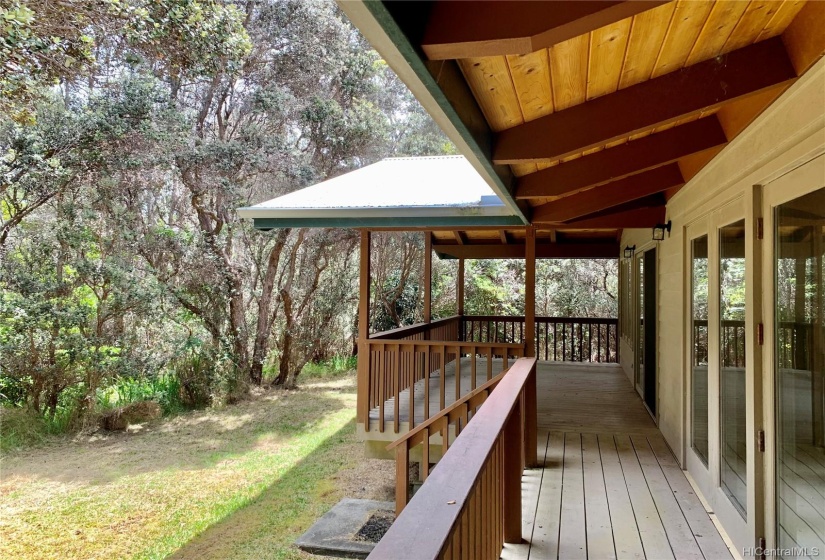 A large covered deck spans the back of the house looking out onto the Ohia forest.