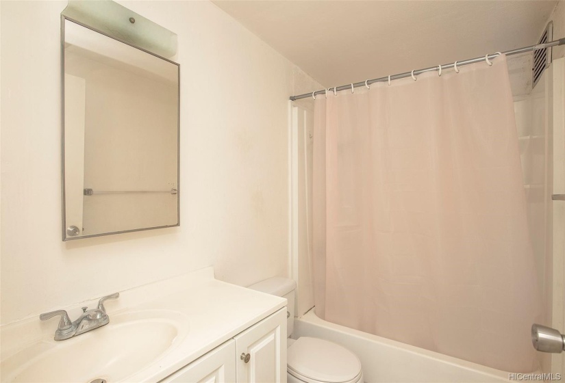 Bathroom w/single vanity and shower + tub combo.