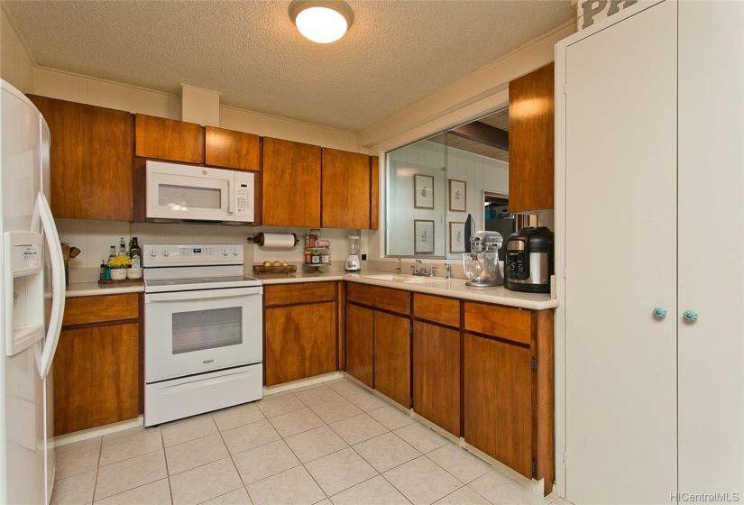 The range and microwave are new. There is a pass through window between the kitchen and family room. The pantry closet is shown on the right.