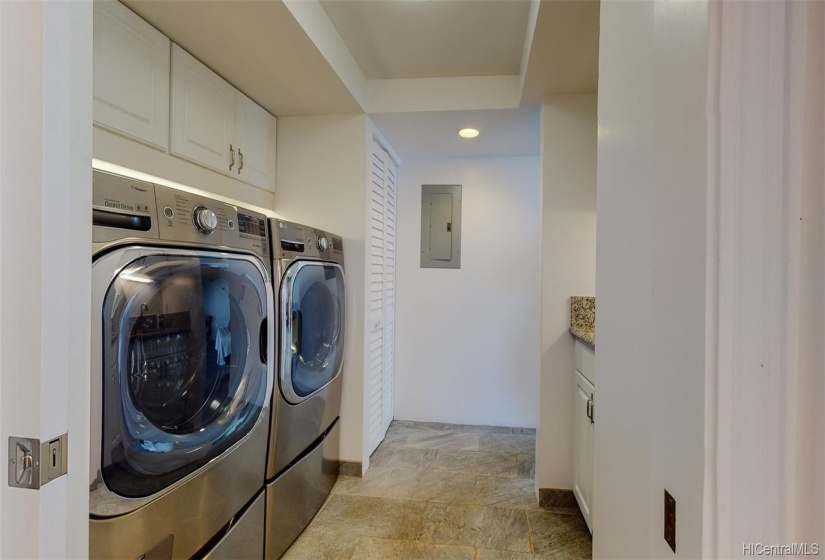 Full size LG stainless steel washer and dryer with risers and storage.