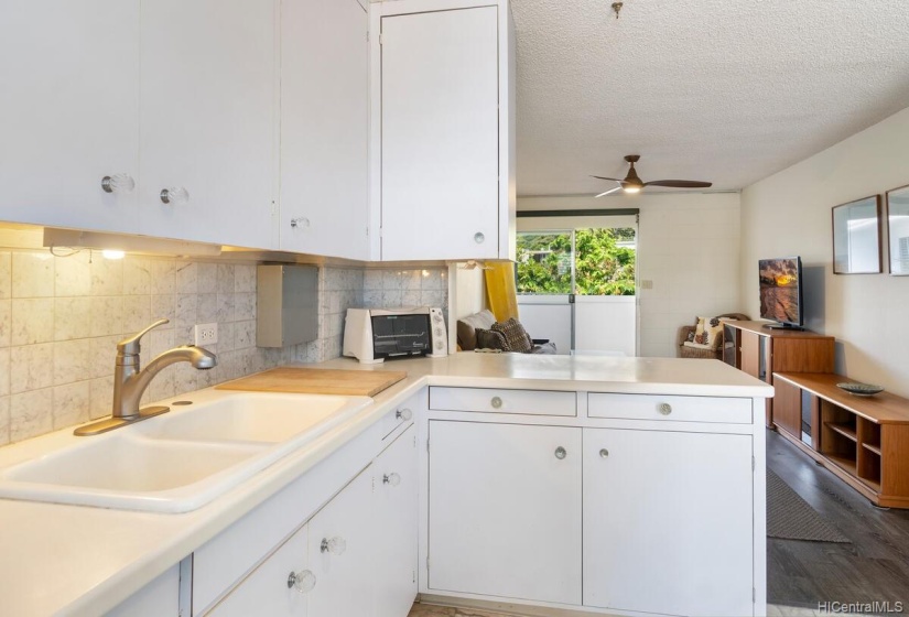 Another view of the kitchen and breakfast bar with a view of the living area in the background