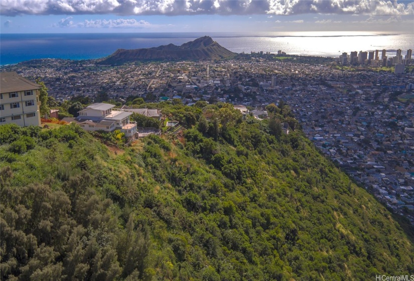 Drone shot showing the end of the driveway, sloped land and views of Diamond Head in the background