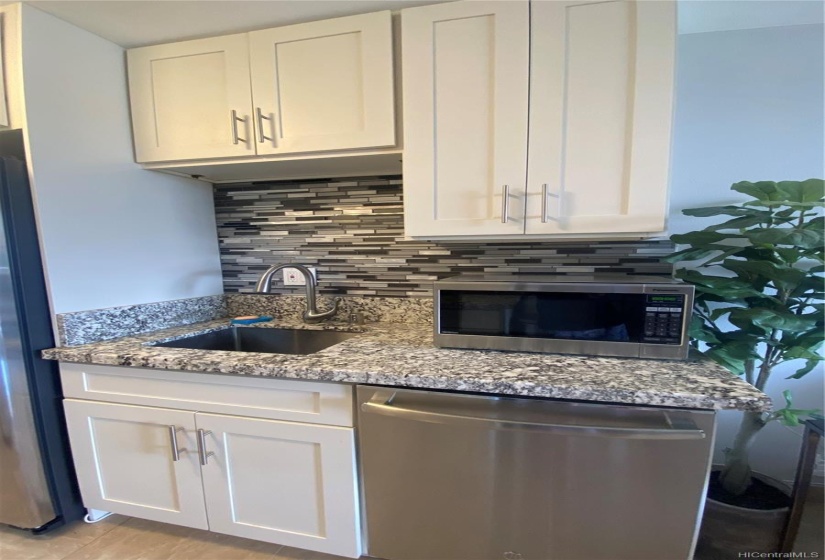 Kitchen cabinets, granite countertop, sink, disposal, backsplash, stainless steel microwave, dishwasher and refrigerator