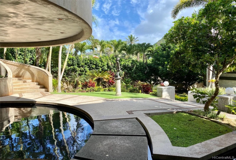 Koi pond with floating steps leading to wellness room and curved stairwell leading to main, grand entrance.