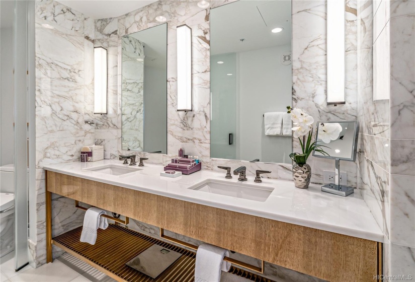 Luxurious master bathroom features marble walls, double vanity marble countertop with separate toilet.