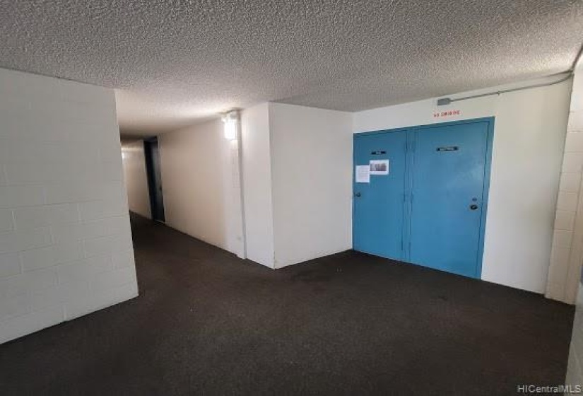 Hallway leading to the elevator with trash room to your right