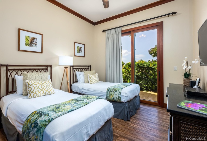 The 2nd bedroom is setup with two twins, features matching new luxury vinyl flooring, ceiling fan, wall-mounted TV, direct outdoor lanai access, closet space.