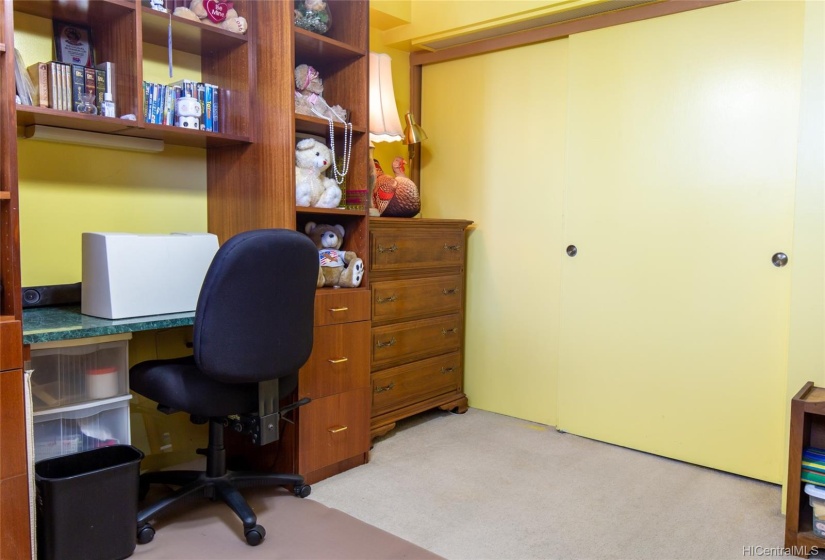 Guest bedroom includes desk and shelving.