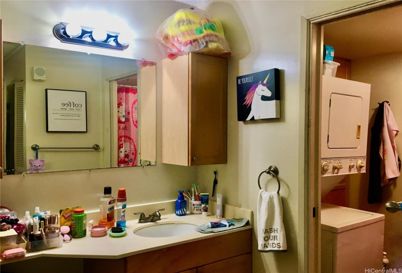 Wide View of Bathroom Vanity Sink and dressing area has Ceramic Tile Flooring, Built in Cabinetry, Pocket Door leads to W/D area, Full Bathtub/Shower, and Toilet.