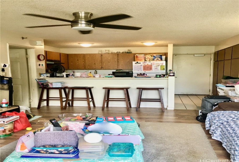 Narrow View of Ceramic Tiled Entry/Kitchen and Counter from Living Area looking towards the Front Door.  Living Room has Wood Laminate flooring (throw rug is Tenants).  To the left is the Large Bathroom w/ Dressing area and W/D, and Bedroom.