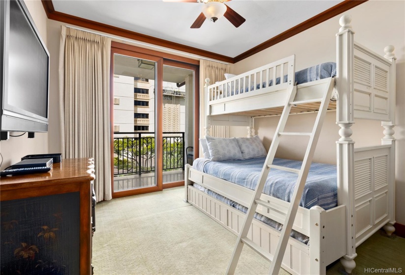 2nd (middle) bedroom featuring a beautiful bunk set, direct access to covered balcony lanai, wall mounted TV, ceiling fan and closet space.