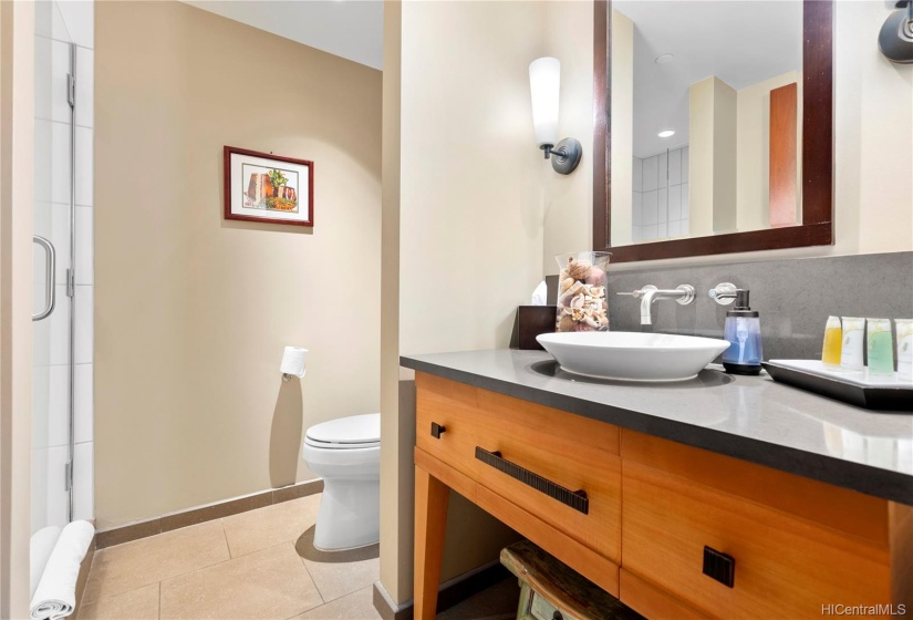 2nd bathroom outside of the 2nd bedroom features a full walk in tiled / glass shower and single sink. Towel racks are wall-mounted behind the bathroom door.