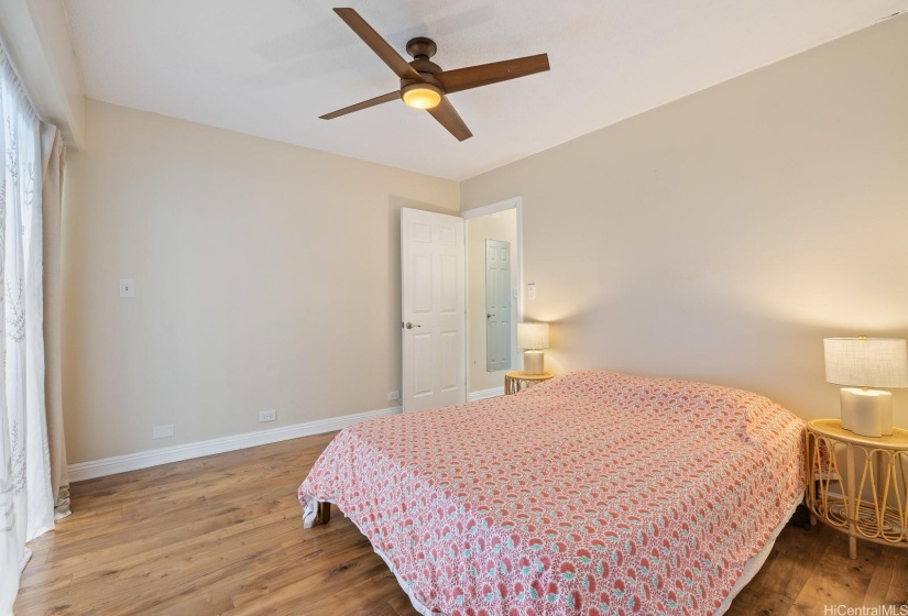 First bedroom with large closet, ceiling fan, window AC, and lanai access.