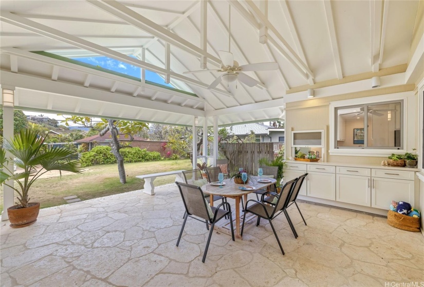 Large outdoor patio with vaulted ceiling, coral flooring and a passthrough to kitchen.