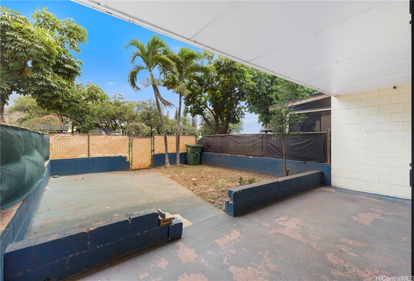 Spacious gated back yard, with gate access opening up to a large grassy area.