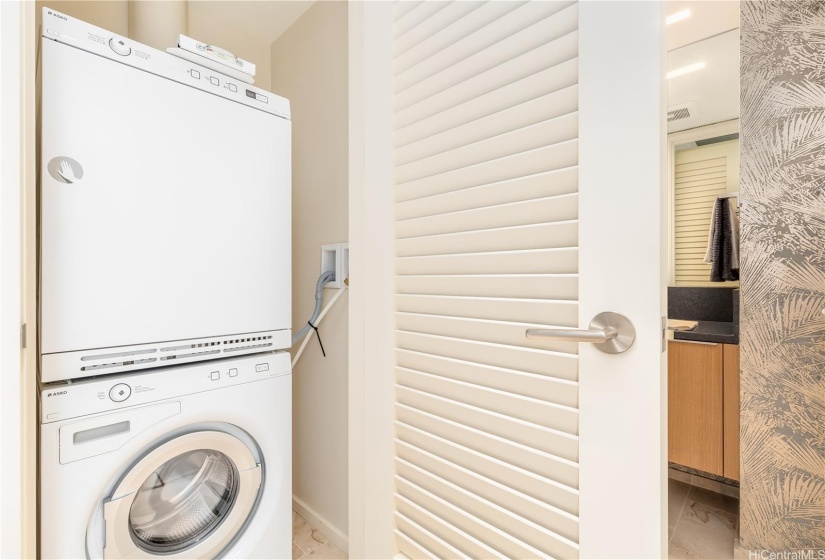 The stacked Asko washer and dryer is adjacent to the guest bathroom.