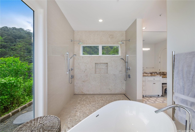 Primary bath walk in shower with 2 shower heads and wall mounted towel warmer.