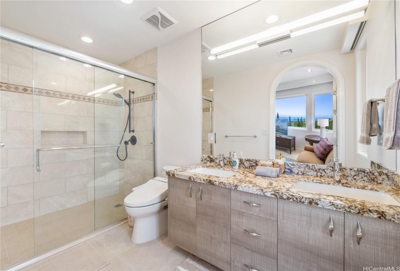 Ensuite bathroom for the second bedroom on the main floor of the home with walk in shower, bidet, unique cabinetry, and granite counter tops.