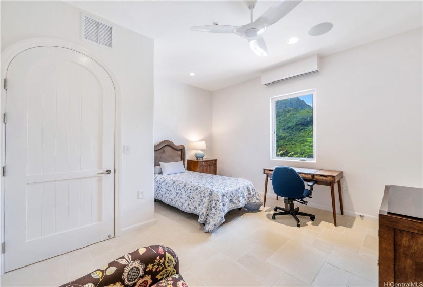 Third bedroom on the main level of the home with mountain views, split a/c, arched door, ensuite bathroom, and limestone tile floors.