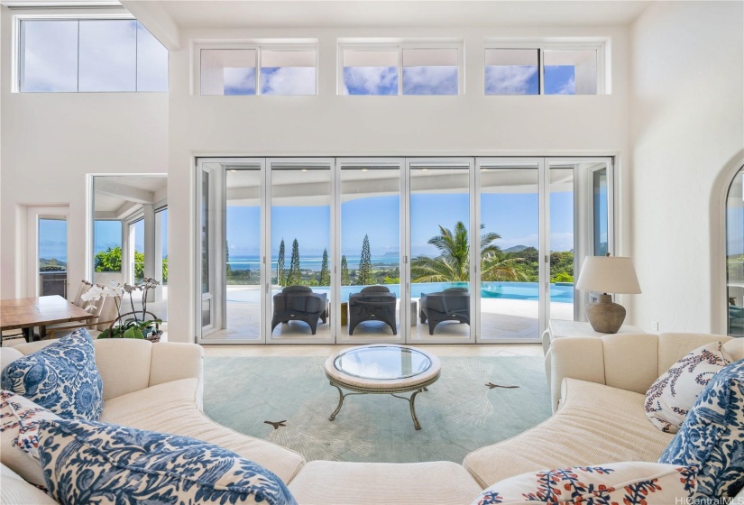 Main living area with vaulted ceilings, retractible glass doors, tons of natural light and a view of the infinity pool and Pacific Ocean.