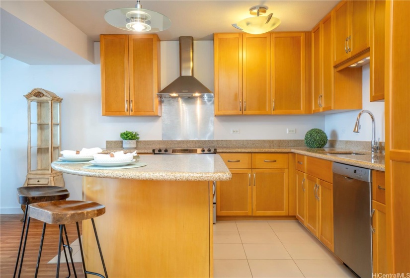 Open Kitchen with island, range hood, dishwasher, and sub-zero fridge to the right of the image.