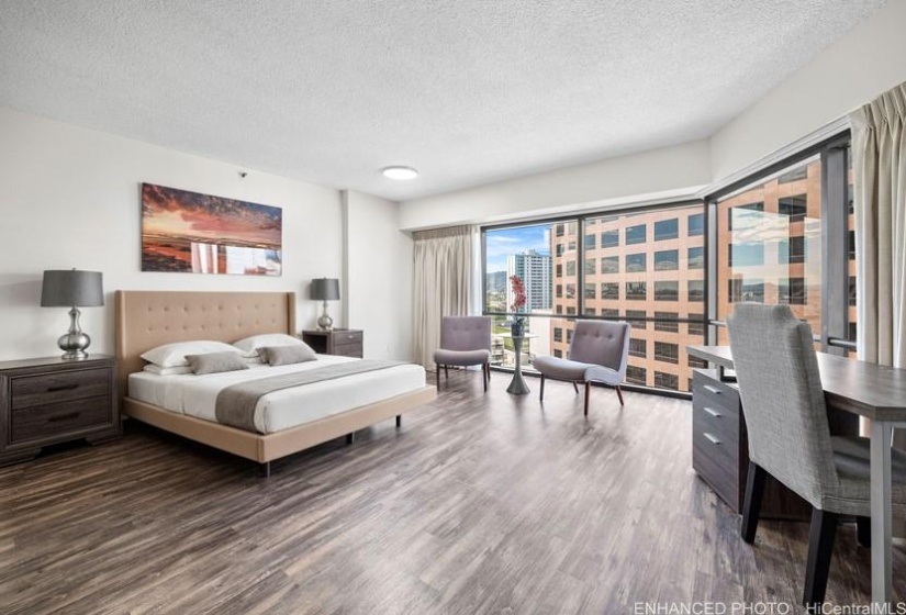 bedroom with huge picture windows and view of the city. Enhanced photo, bed is virtual staging.