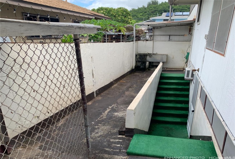 Makai side of Main House: Entry to Unit 2 (Basement) - Full bathroom external to unit around corner from stairs (not pictured) (Enhanced: Signage blurred)