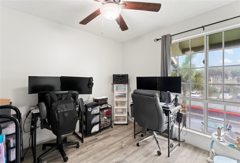 1st bedroom features floor to ceiling windows and a ceiling fan.