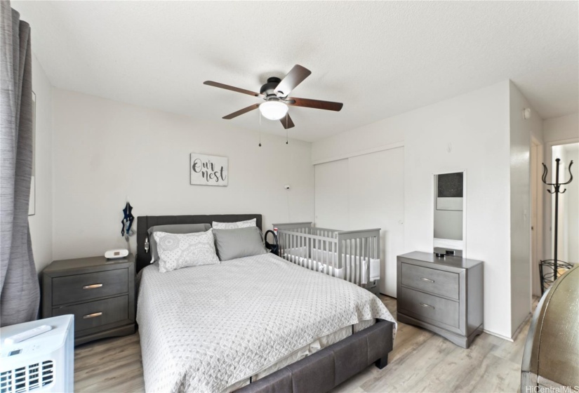 Primary bedroom features 2 closets, a portable window ac and ceiling fan.