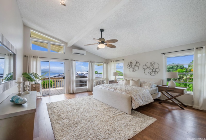 The spacious primary suite features high vaulted ceilings, a ceiling fan, a split AC unit, lots of windows and a sliding door to the second story lanai. Take in the views of Kaneohe Bay and the mountains from your bed!