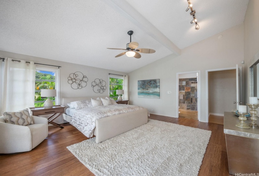 The spacious primary suite features high vaulted ceilings, a ceiling fan, a split AC unit, lots of windows and a sliding door to the second story lanai. The large en suite bath features vaulted ceilings, a double vanity, two closets and shower and a water closet for privacy.