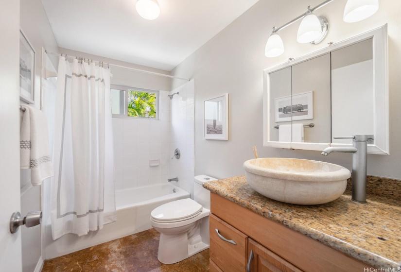 The additional upstairs bathroom features a vessel sink and vanity, bathtub and shower.