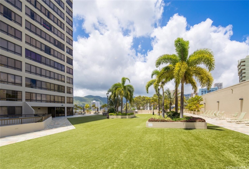 Recreation area with party room at the end of the building, picnic tables, BBQ's, artificial turf, lounge chairs, possible jogging path around the perimeter.