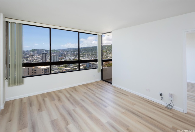 Living room with new installed 2024 luxury vinyl flooring. Forever views of Punchbowl, Tantalus, Manoa including the University of Hawaii Sports Complex.