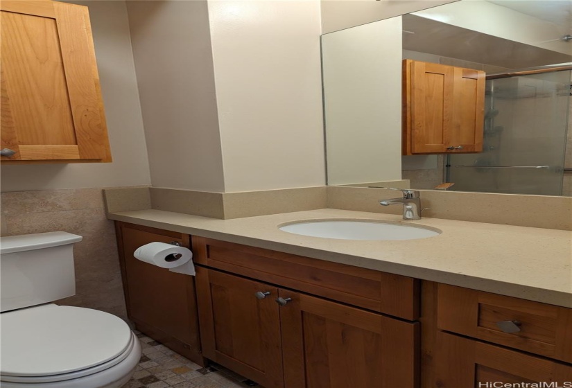 Bathroom features newer cabinets, quartz counter tops, remodeled shower and tile flooring