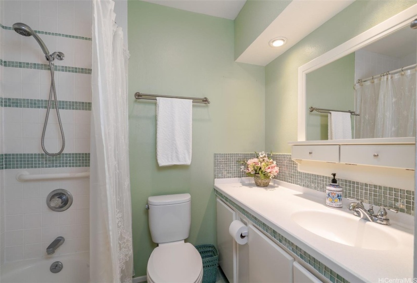 Primary bedroom ensuite bathroom with Corian countertops and tile accents.