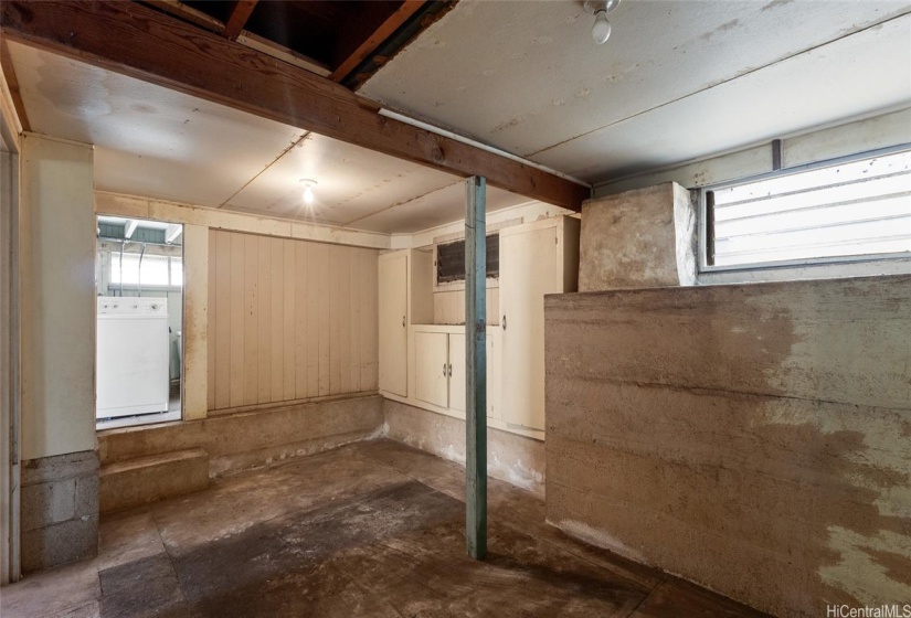 Large basement area under the living room has built in cabinets and solid concrete wall, seen on the right.