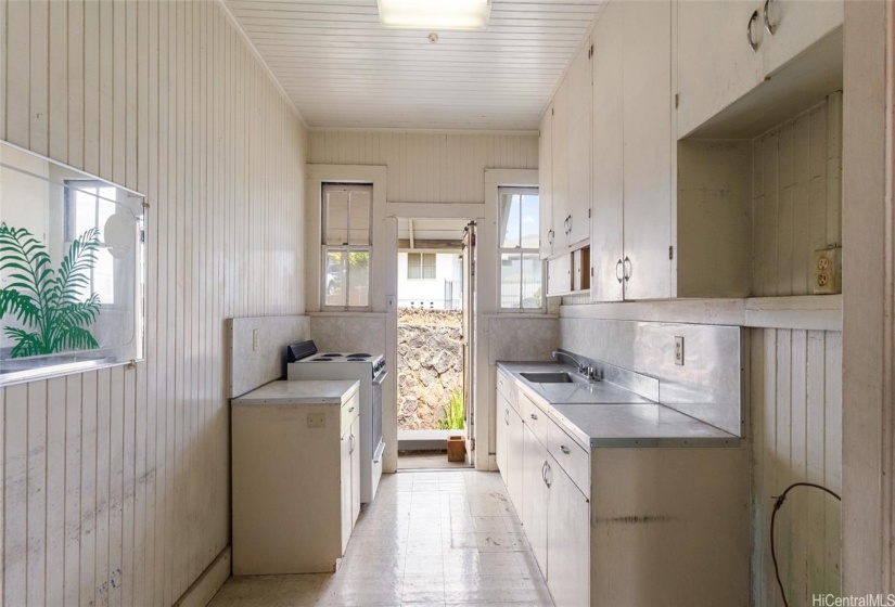 Kitchen has original cabinetry and a side entry to the house.