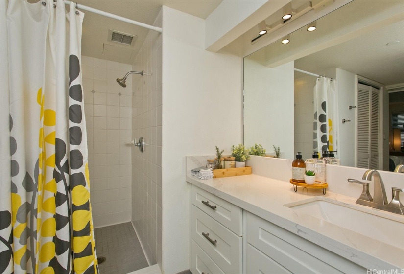 Inviting renovated bathroom with newer cabinets and quartz counters.