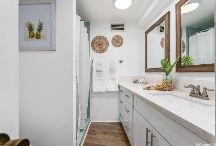 The primary bathroom boasts a beautifully tiled shower and ample counter space.