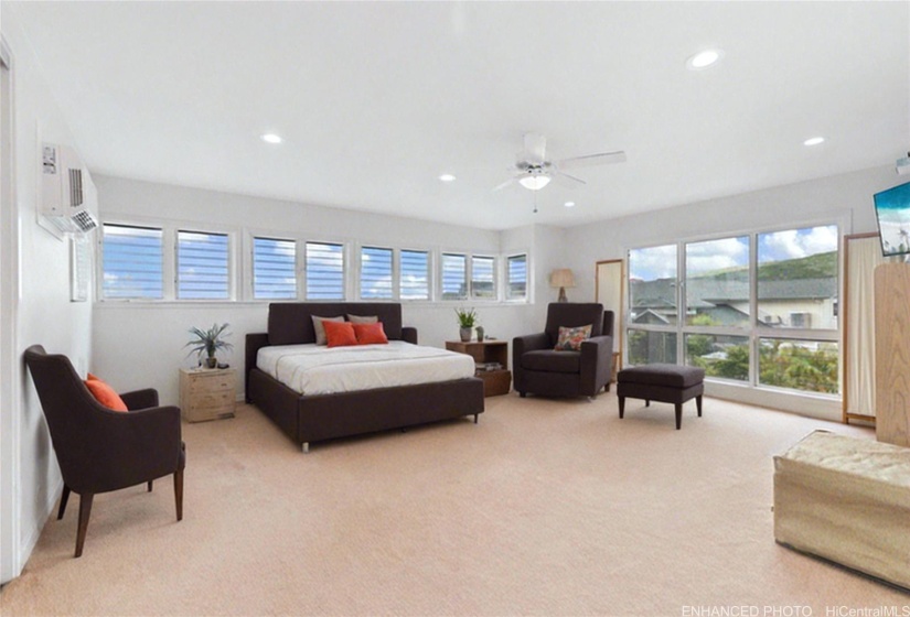 Enhanced photo with virtual staging of the HUGE upstairs primary suite, with picture windows of the mountains.