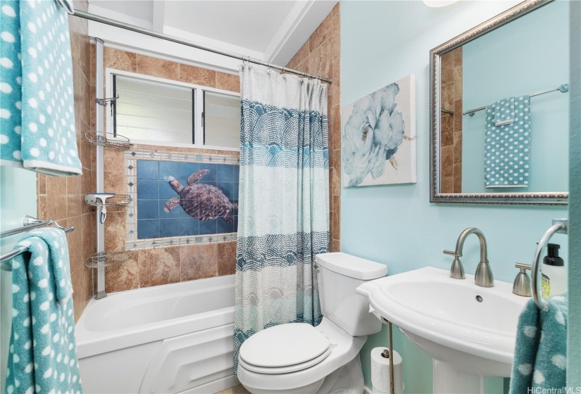 The bathroom is adorned with graceful sea turtle tile art.