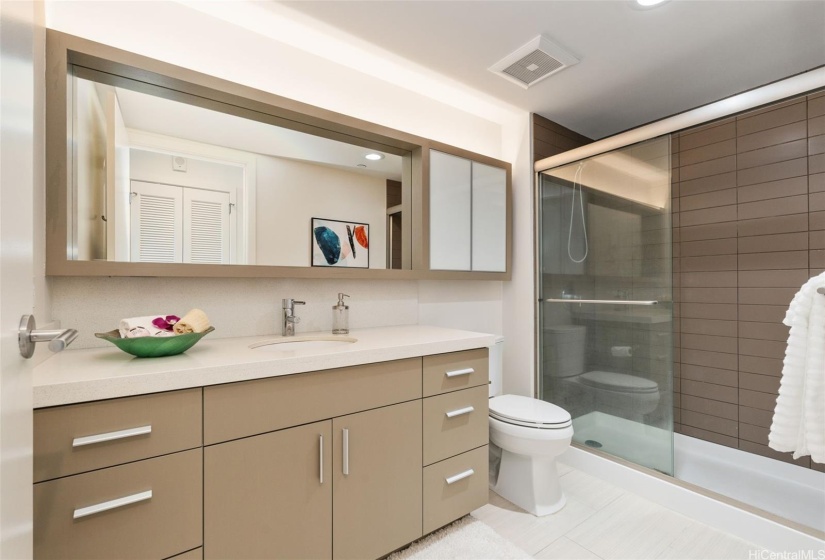 Primary suite bathroom with durable and cool ceramic tile, single basin vanity with quartz counter and lots of storage, and easy to access step-in shower.