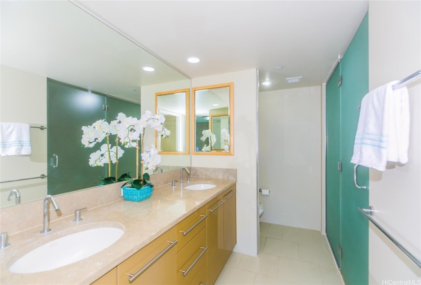 The large primary bathroom feature luxurious polished stone shower/soaking tub areas with glass enclosure and double vanity sinks.