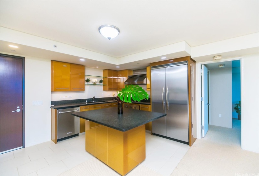 The high end Viking appliances include glass cooktop, built in oven, range hood, and cabinet depth refrigerator. Doorway leading to the primary bedroom on the immediate side of the kitchen.