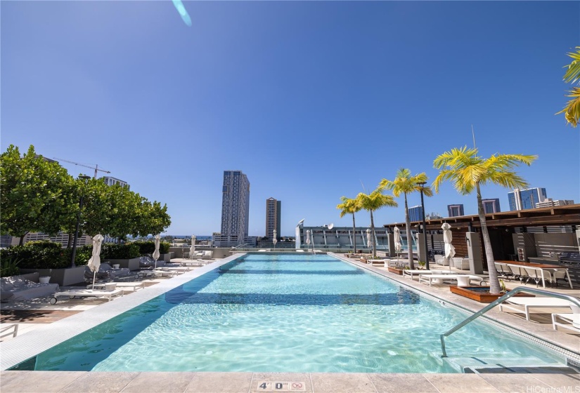 Infinity pool adjacent to pool-chairs, pool sofas, and BBQ cabanas